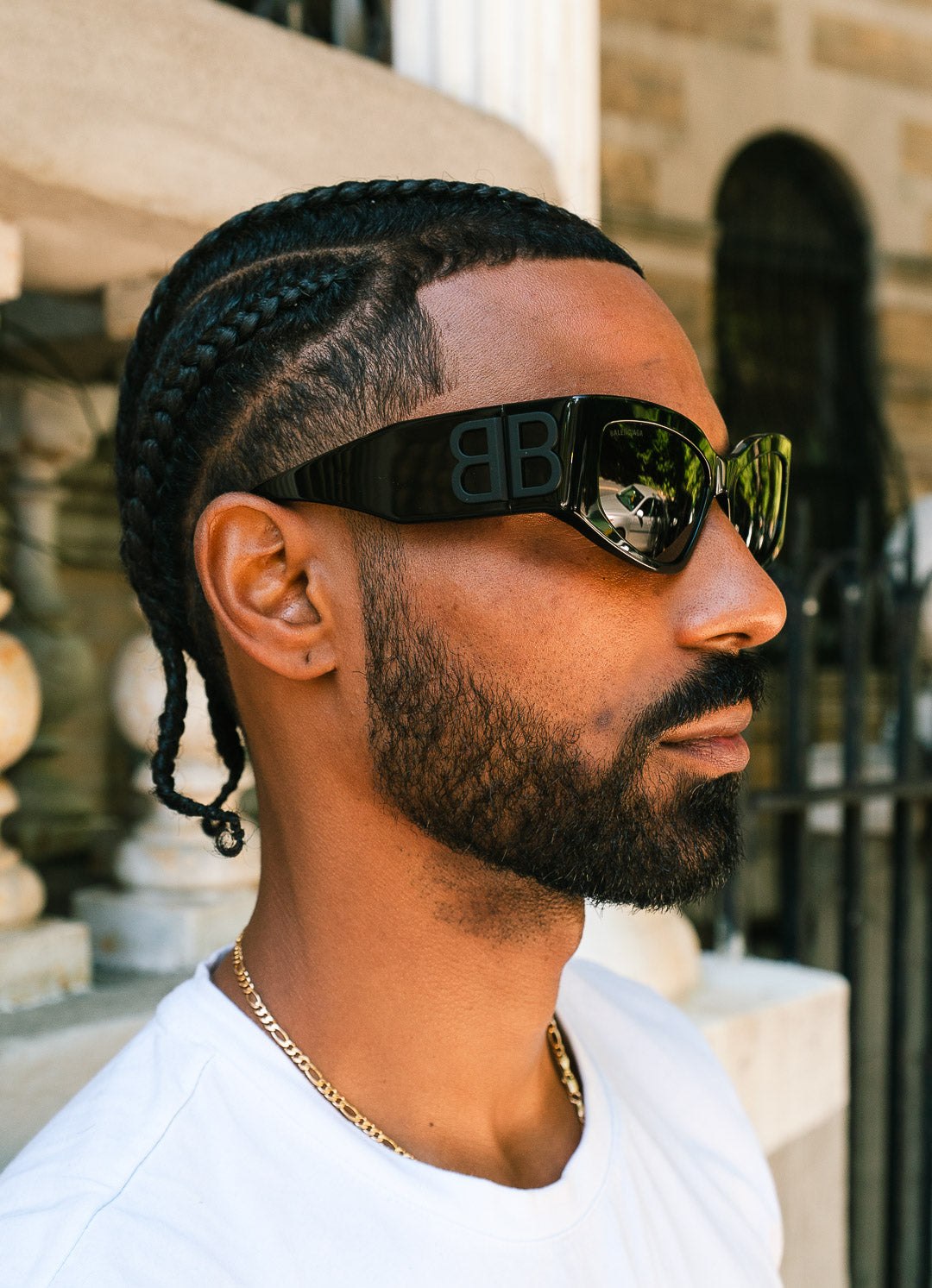 Man wearing sunglasses with a brand logo, standing outdoors.
